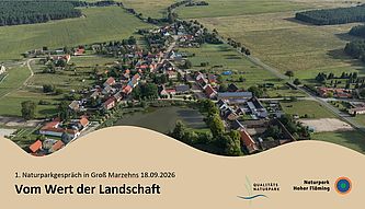 Blick auf Dorf und Landschaft aus Vogelperspektive. Im unteren Bereich eine