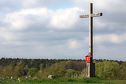 Holzkreuz mit rotem Briefkasten auf einer Anhöhe